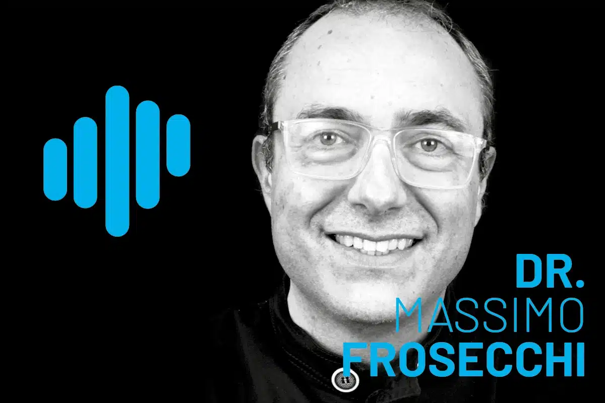 Massimo Frosecchi portrait featuring clear glasses in a grayscale tone with a blue logo silhouette on the left; a professional, friendly headshot.