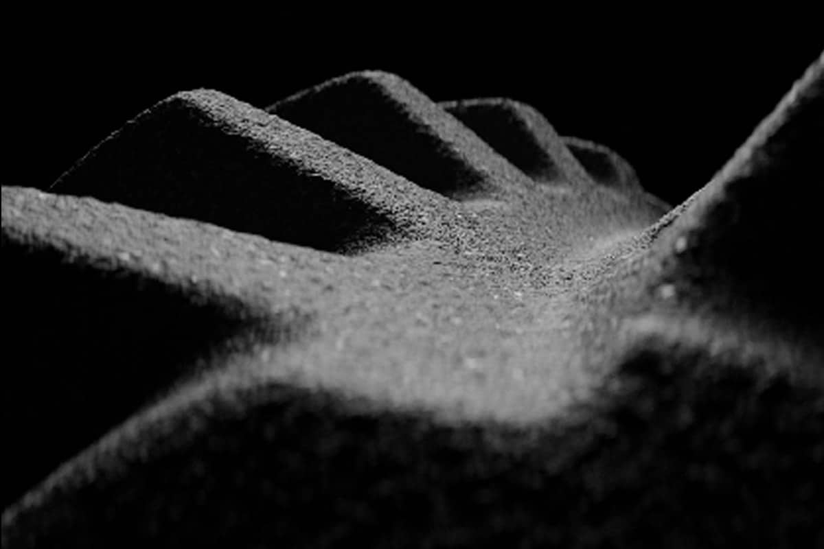 Close-up view of a textured surface with ridges and valleys, resembling a wave-like pattern in a monochromatic tone.