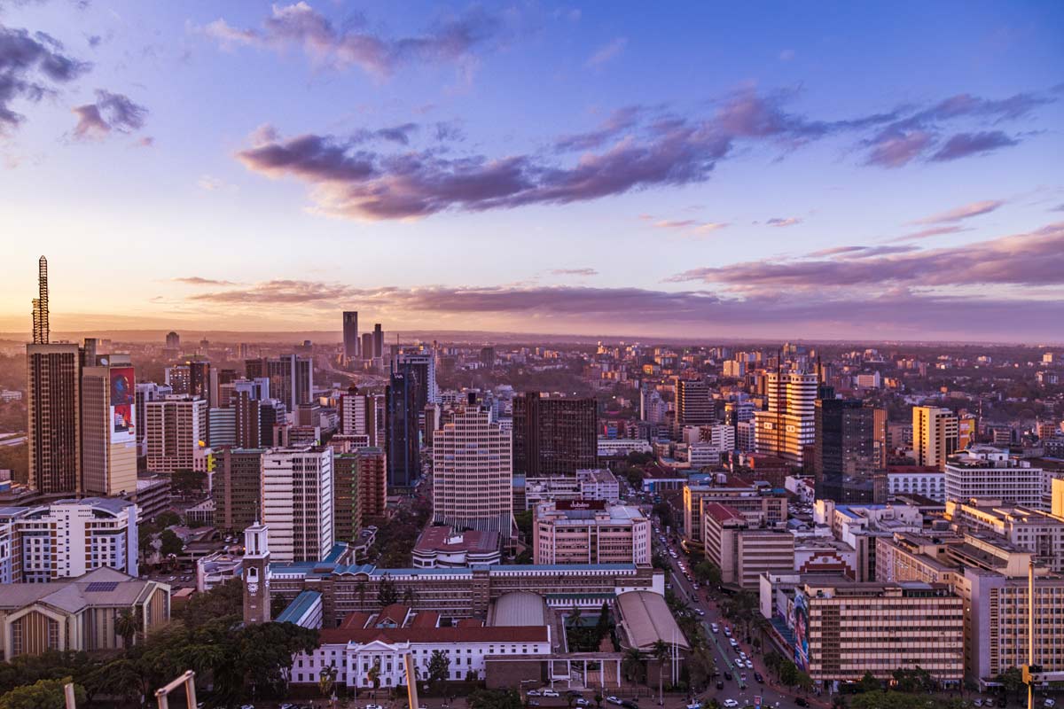 Nairobi city skyline at sunset featuring high-rise buildings against a purple-orange sky, capturing the urban landscape and expansive horizon.