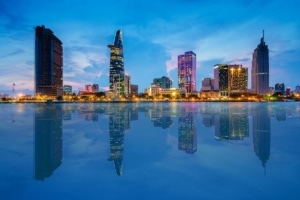 Ho Chi Minh skyline at dusk with mirrored skyscrapers on calm water under a blue sky, supporting Large Language Models for alveolar ridge preservation.